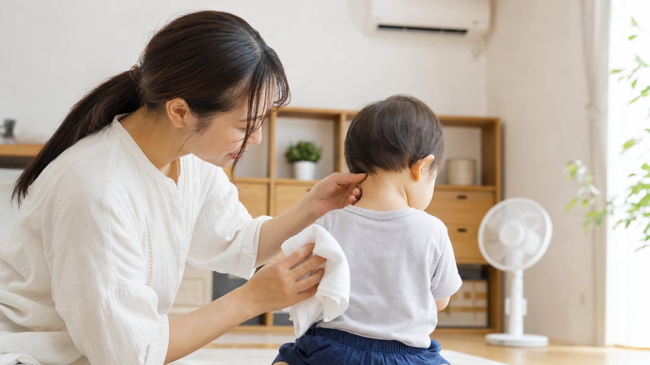 母親が自宅で幼児の首の汗と赤みを確認し室温と衣類を調整する様子