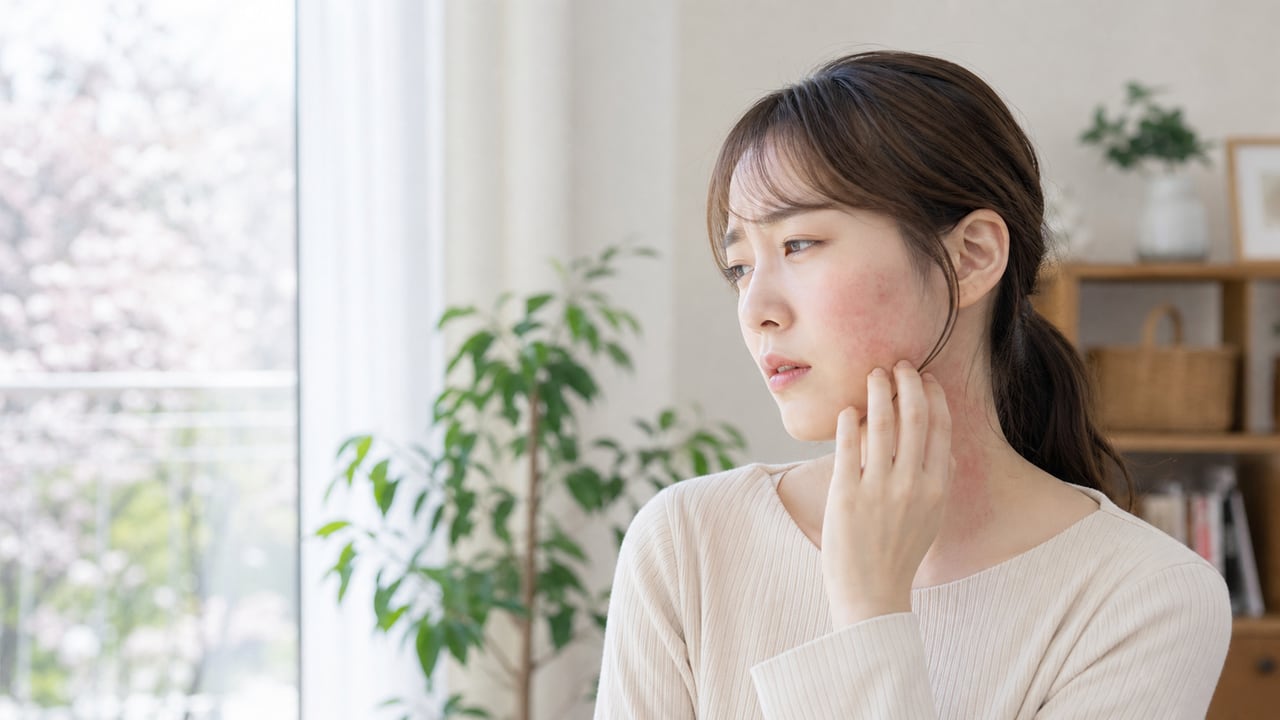 自宅で頬と首の赤みを確認しながら花粉対策とスキンケアを見直す成人女性