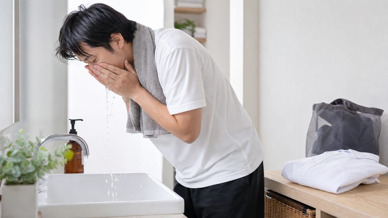 運動後の洗浄と着替え 運動後に顔をやさしく洗い清潔な衣類へ着替える成人男性