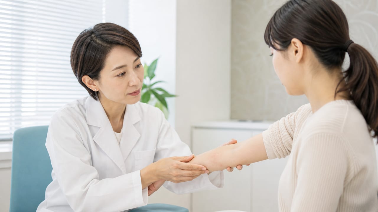 虫刺されが疑われる腕の皮膚を皮膚科医が診察する様子