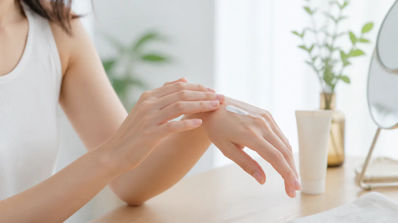 日焼け止めを塗る女性の手元、紫外線から肌を守る正しいUVケアの重要性